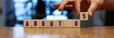 Om oss – CCMS Hand som placerar bokstavsklossar som tillsammans bildar ordet ”ABOUT US”.